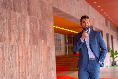 Business or finance corporate man at the entrance of an event in a hotel with the phone