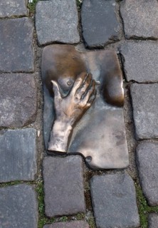 A miniature floor sculpture of a hand and a female titmouse on the Oudekerksplein