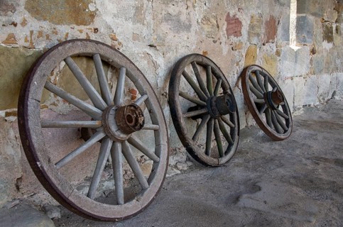 Historic old carriage wheels of carriages stand against an old sandstone wall