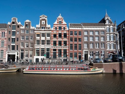 Historic merchant houses on the Herengracht in the old town and tourist boat