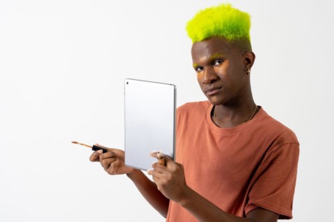 A gay black ethnic man putting on makeup