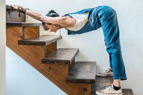 A woman doing stretching exercises on the stairs of her home. Wellbeing concept