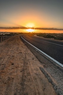 Empty asphalt road through the desert or dunes. Sunrise over the road