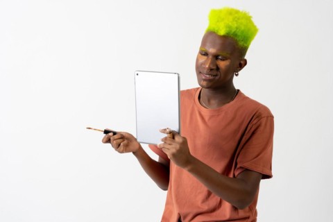 A gay black ethnic man putting on makeup