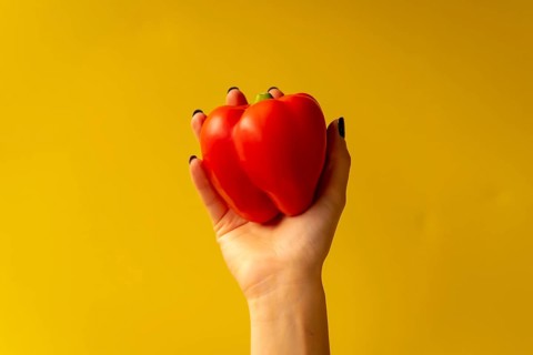 Woman's hand with a vegetable on a yellow background