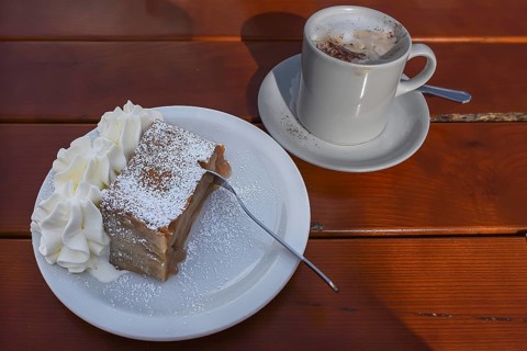 Apple strudel with cream and a cup of cappuccino served in a cafe