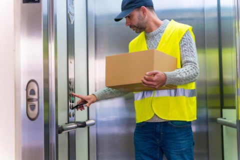 Young delivery man in protective uniform at online order delivery