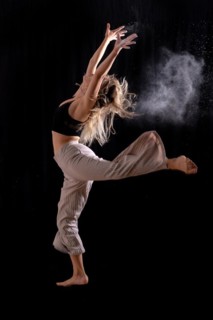 Young dancer performing a jump on a black background