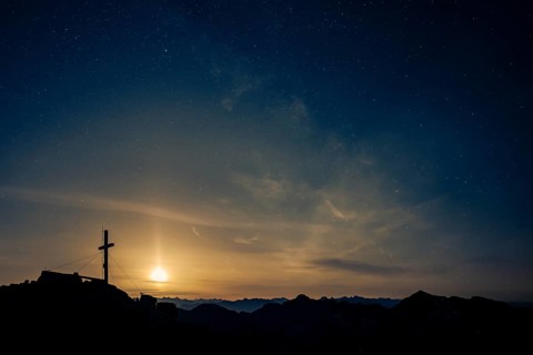 Summit cross of the Namloser Wetterspitze at full moon and Lechtaler Alps