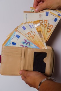 Woman's hands taking euro banknotes out of her wallet with white background and copy space