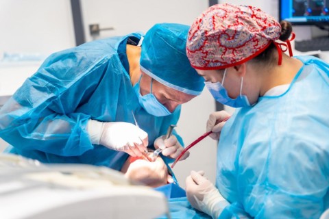 Doctors in blue gowns performing a complicated operation on a patient