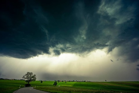 Road and meadows with thunderstorm sky in the background