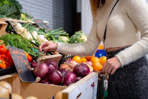 Woman buying vegetables and greens in grocery store