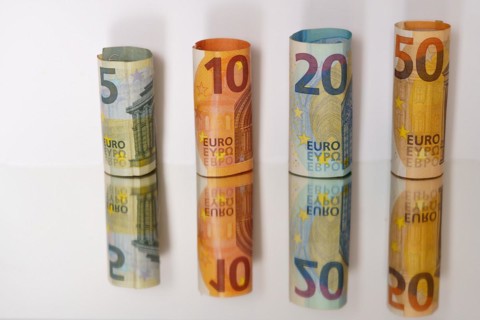 Rolled euro banknotes reflected in a mirror with copy space