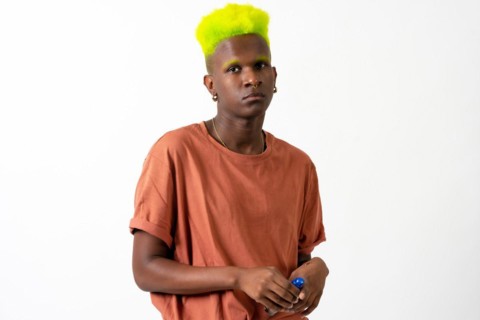 An androgynous black man posing in a studio on a white background