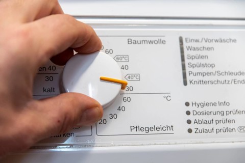 Hand on the temperature control of a washing machine
