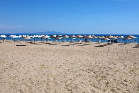 Straw parasols on the sandy beach on the Aegean Sea