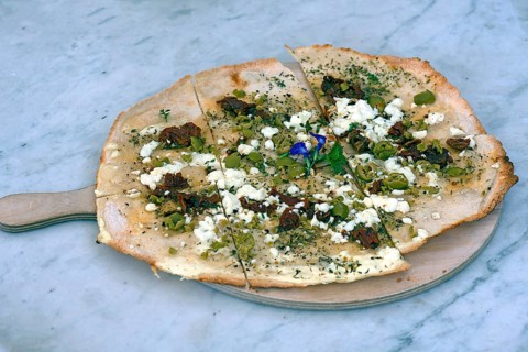 Flammkuchen with olives dried tomatoes and feta cheese on a wooden board