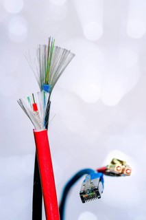 A cut-open patch cable with RJ45 connector and a cut-open optical fibre cable with connector and shielding on a white background