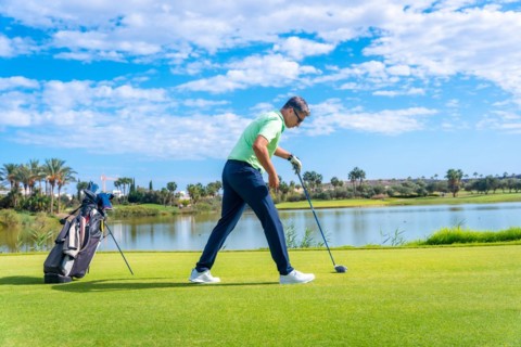 Male golf player on professional golf course. Golfer with golf driver stick preparing the shot