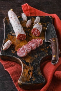 Fermented salami sausages on wooden cutting board cut on slices