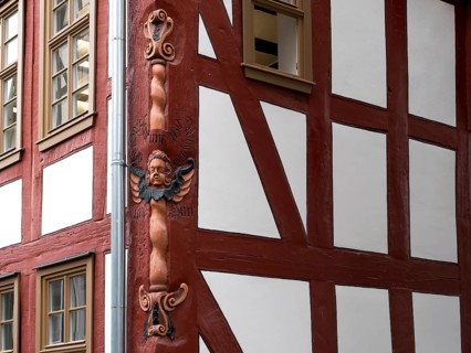 Colourful carved figures on the corner of the half-timbered house