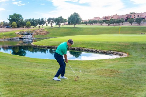 Man playing golf at golf club by a lake