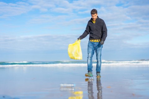 Volunteer man collecting garbage or plastic on the beach. ecology concept