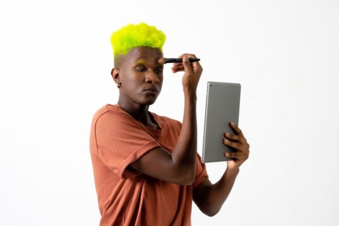 A gay black man putting on makeup