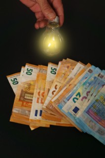 Lighted light bulb with euro banknotes in the background on a black background