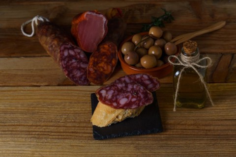 Tapa of iberian sausage on rustic bread with olive oil on a wooden board with black background