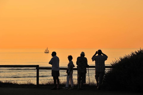Tourists looking at sailing ship at sunset at Saint-Denis-d'Oleron on the island Ile d'Oleron