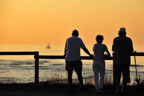Tourists looking at sailing ship at sunset at Saint-Denis-d'Oleron on the island Ile d'Oleron