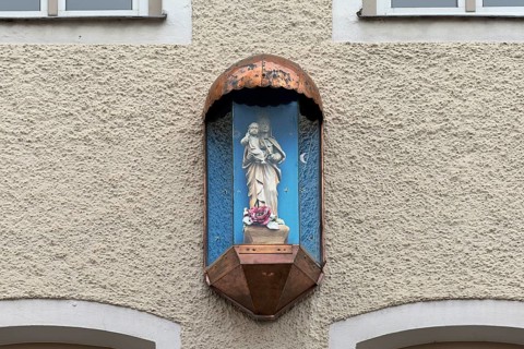 Sculpture of the Virgin Mary in a glass case on a residential house