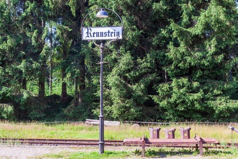 Station lantern with place-name sign and bench made of rusty crash barriers