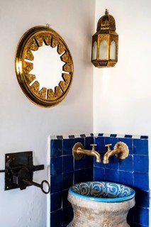 Traditional wash basin and golden mirror and lamp in the corner of the riad's bedroom