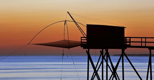 Traditional carrelet fishing hut with lift net on the beach at sunset