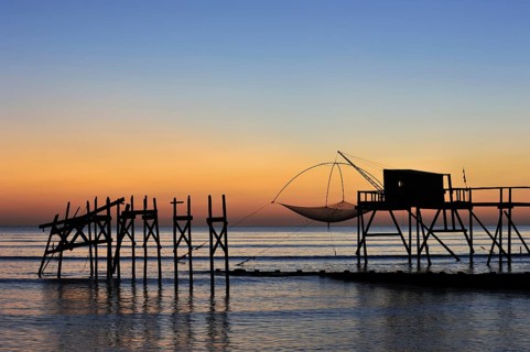 Traditional carrelet fishing hut with lift net on the beach at sunset