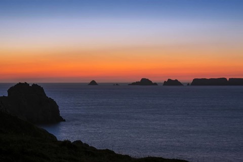 Sea cliffs at the Pointe de Pen-Hir and Les Tas de Pois sea stacks silhouetted against sunset on the Crozon Peninsula