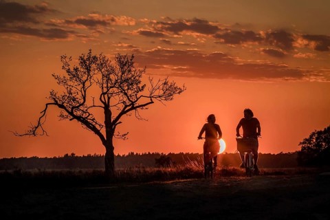 Young couple cycling in the countryside at dusk