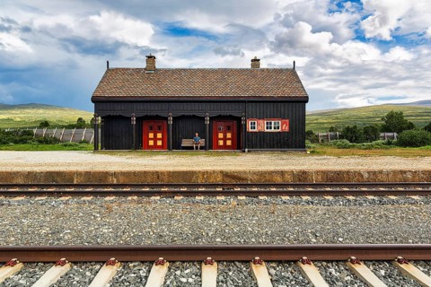 Man sitting lonely on a bench looking at the tracks