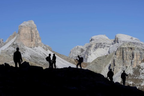 Mountain walkers silhouetted against Torre dei Scarperi