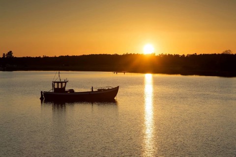 Fishing boat silhouetted against sunset
