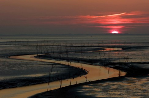 The shipping channel in the mudflats for shrimp trawlers in Wremertief at sunset