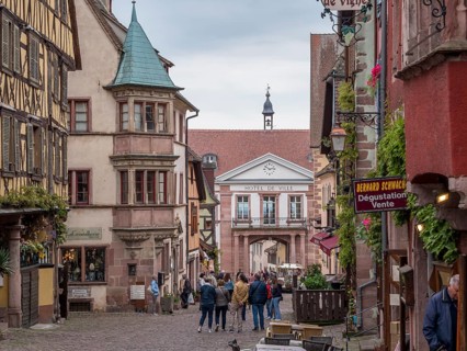 Colourful half-timbered houses and tourists in the Rue du General de Gaulle and in the background town hall Hotel de Ville