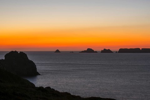 Sea cliffs at the Pointe de Pen-Hir and Les Tas de Pois sea stacks silhouetted against sunset on the Crozon Peninsula