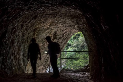 Two walkers with torch entering tunnel on the Sentier Martel path in the Gorges du Verdon