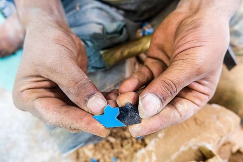 Craftsman showing hand made tiny ceramic tiles that perfectly fit each other in pottery factory in Fez