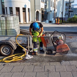 Road worker in protective clothing cutting asphalt at a road construction site