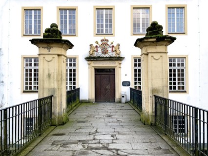 View over bridge from moat to entrance door of historic moated castle Burg Schloss Borbeck